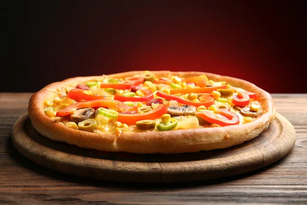 Delicious pizza with vegetables and meat on dark red background