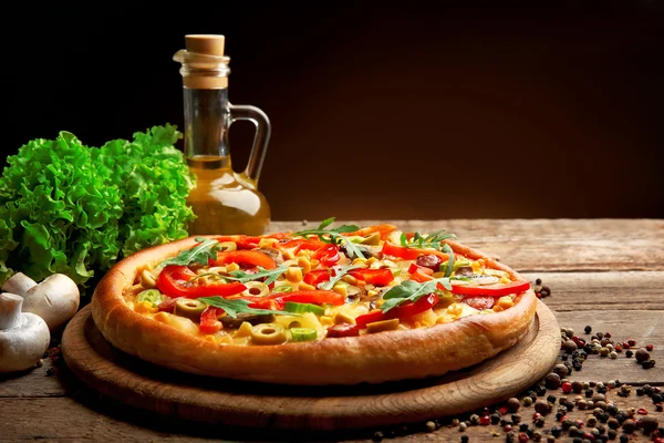 Delicious pizza with salad and oil on brown background
