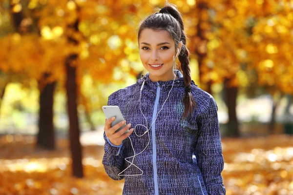 Woman holding phone in autumn park