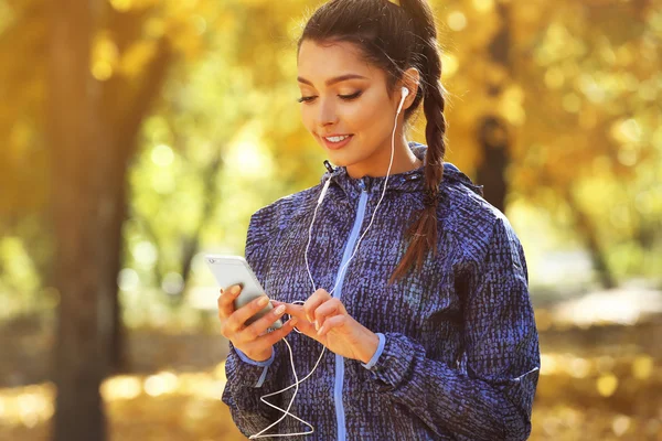 Woman holding phone in autumn park