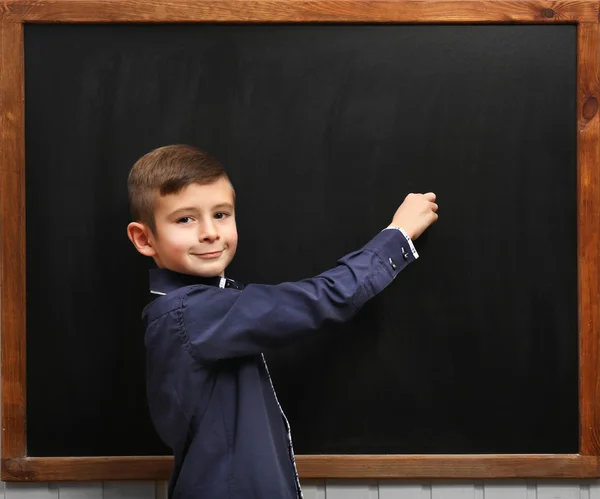 Cute boy posing at clean blackboard