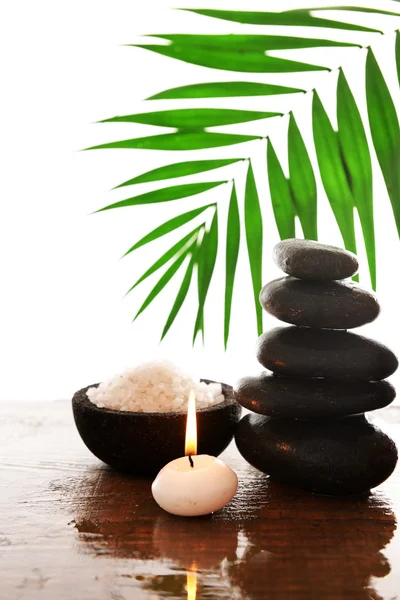 Spa stones with candle, green leaves and sea salt, isolated on white