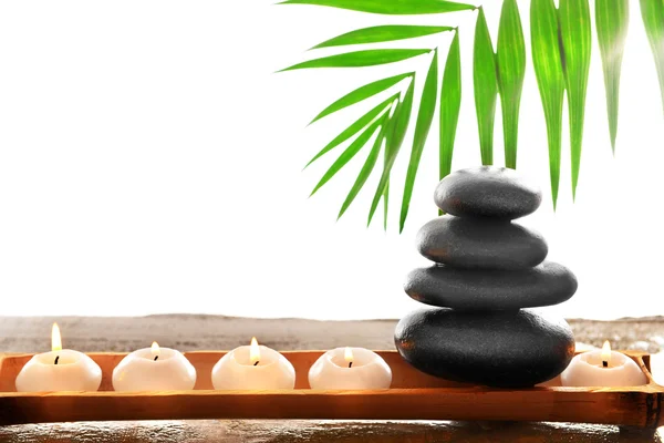Spa stones with candles, green leaves and bamboo, isolated on white