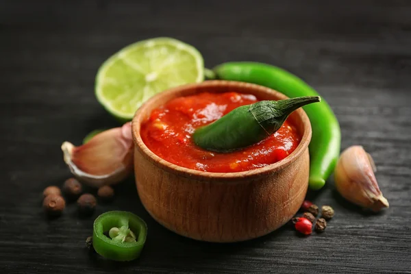 Homemade hot sauce and spices on dark wooden background