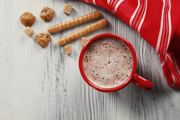 Red cup of hot cacao and sweets  on wooden background