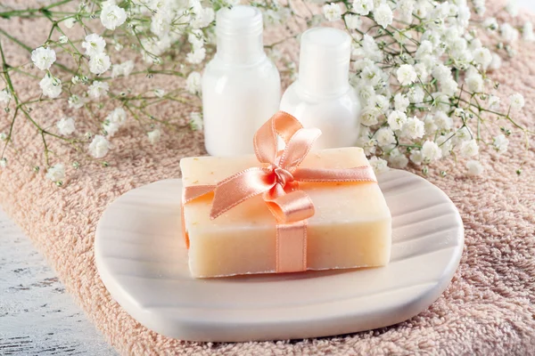 Soap with ribbon on a dish over towel background, close up