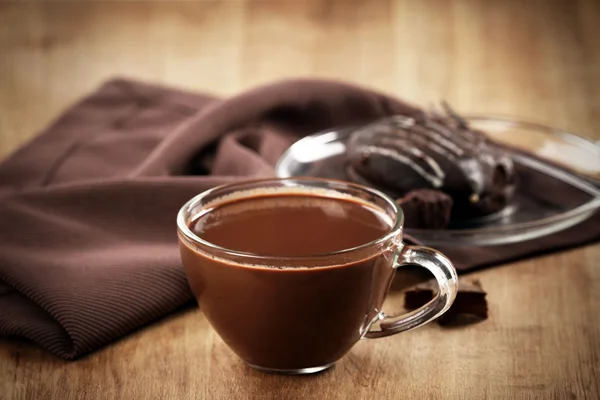 Cup of cacao with chocolate and napkin on wooden table