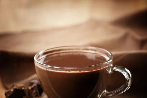 Cup of cacao with chocolate and napkin on wooden table