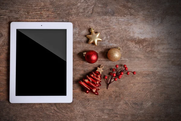 Tablet and Christmas decor on wooden background