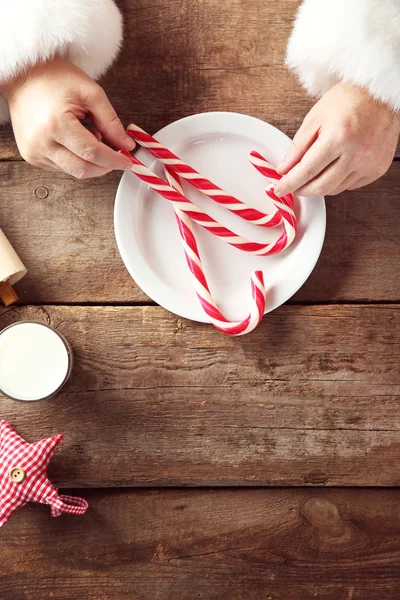 Christmas concept. Santa hands take candies and milk glass, close up