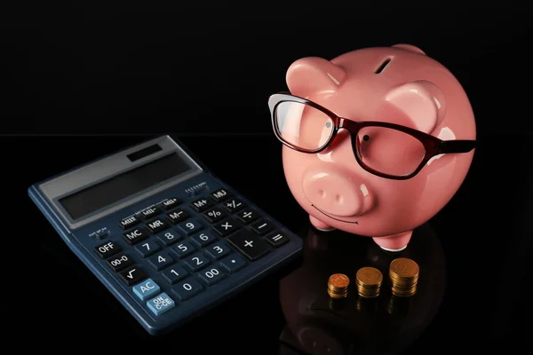Piggy bank with glasses,coins and calculator