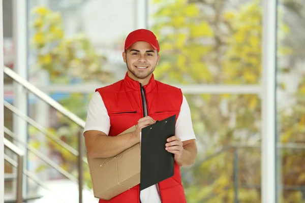 Postman in red uniform holding package