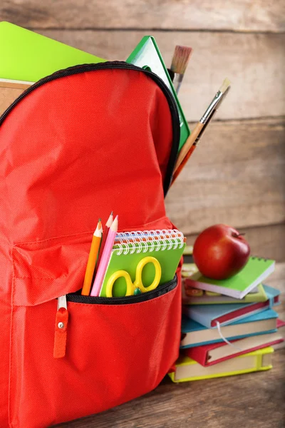 Red backpack with books and apple