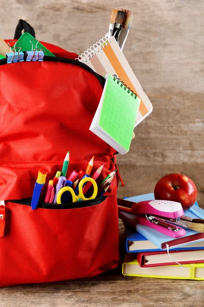 Red backpack with books and apple