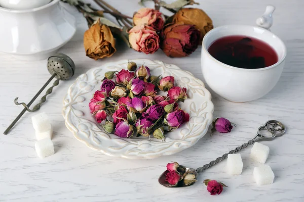 Tea and tea rose flowers on table closeup