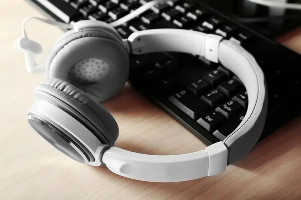 Headphones and keyboard on wooden table