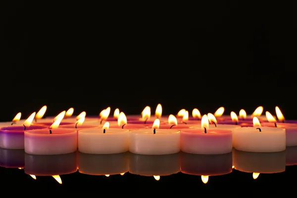 Many burning small candles on dark background