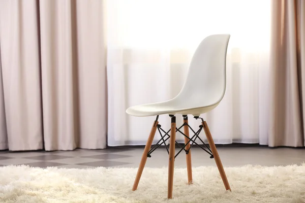Stylish conception with white chair on light room background