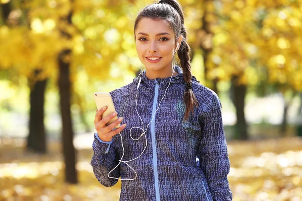 Woman holding phone in autumn park