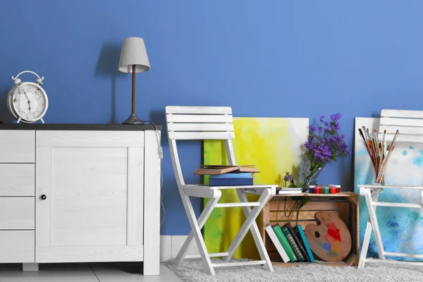 Room design with white furniture, bookcase, pictures, flowers over blue wall