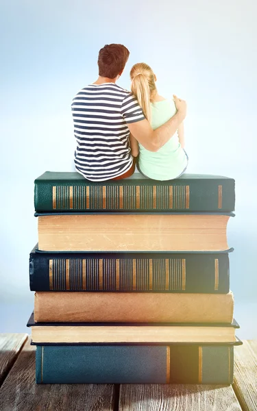 Lovely couple sitting on stack of books