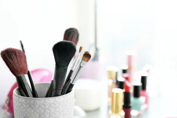 Makeup tools with cosmetics on a table, close up