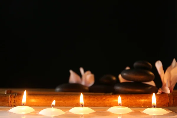 Spa still life with candles in water on dark background