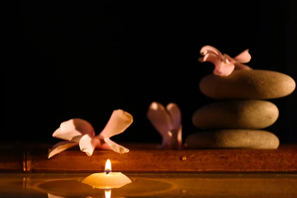 Spa still life with candle in water on dark background