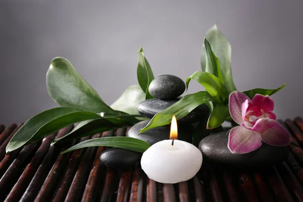 Spa still life with beautiful flower and candlelight on bamboo sticks closeup
