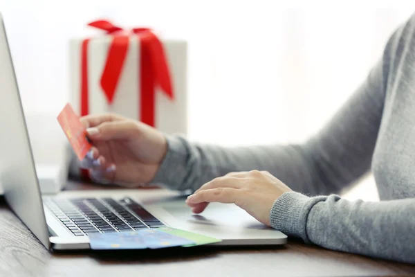 E-commerce concept. Woman with credit card, laptop and gift box, close up