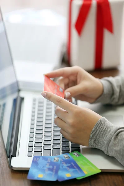 E-commerce concept. Woman with credit card, laptop and gift box, close up