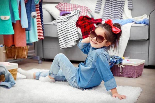 Little girl in the room with a lot of clothes