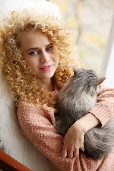 Young woman and cat beside window