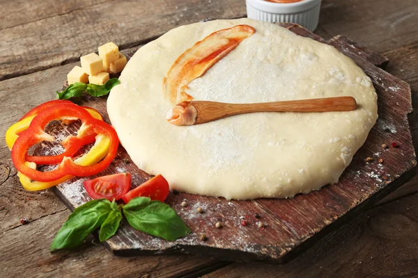 新鲜的面团准备用西红柿比萨饼,并且在木板上