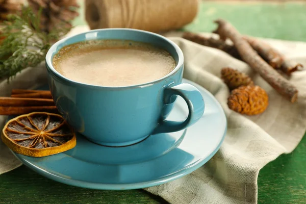 Cup of coffee with sweet spices on napkin on green wooden background