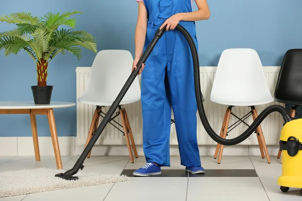 A woman  vacuuming the floor