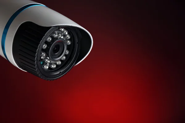 Security CCTV camera on red background, closeup