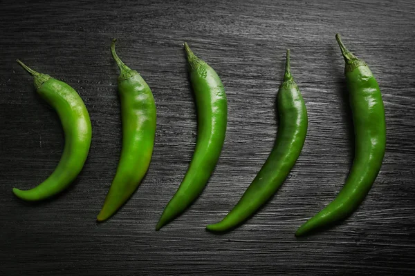 Green chili peppers on dark wooden background