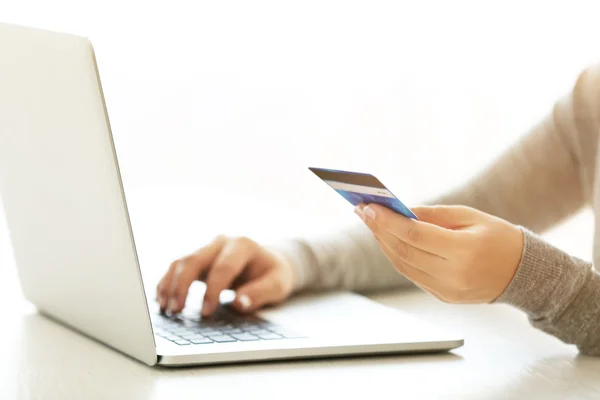 E-commerce concept. Woman with credit card and laptop, close up