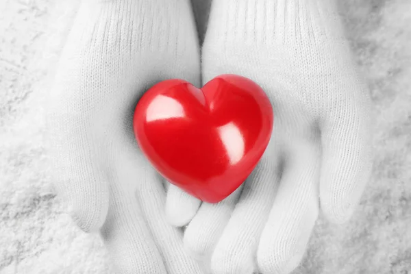 Hands in gloves holding red heart