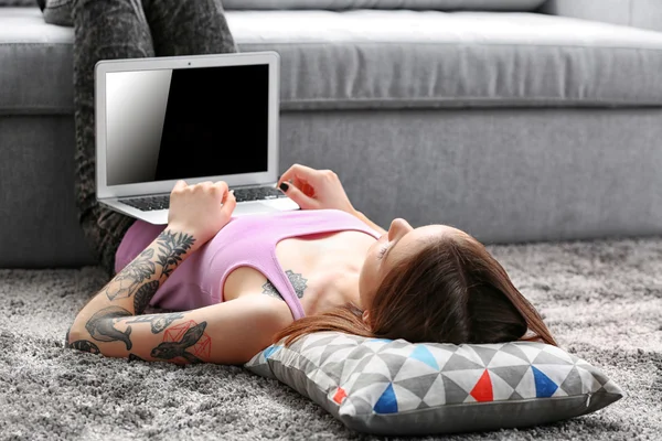 Woman with the laptop lying on the floor