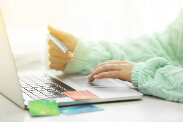 E-commerce concept. Woman with credit card and laptop, close up