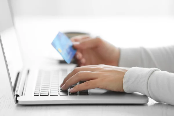 E-commerce concept. Woman with credit card, laptop and cup of coffee, close up