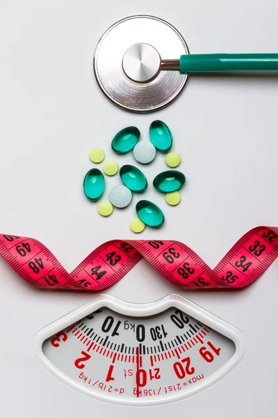Pills stethoscope measuring tape on scales. Health care