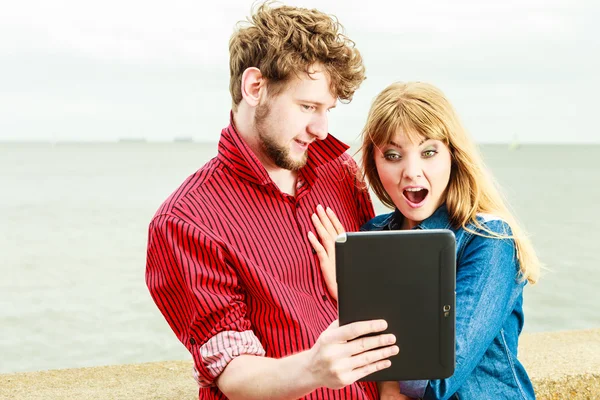 Young couple with tablet by seaside outdoor
