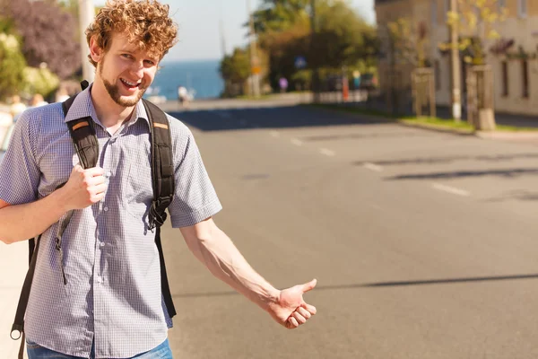Happy man hitchhiking on summer vacation.