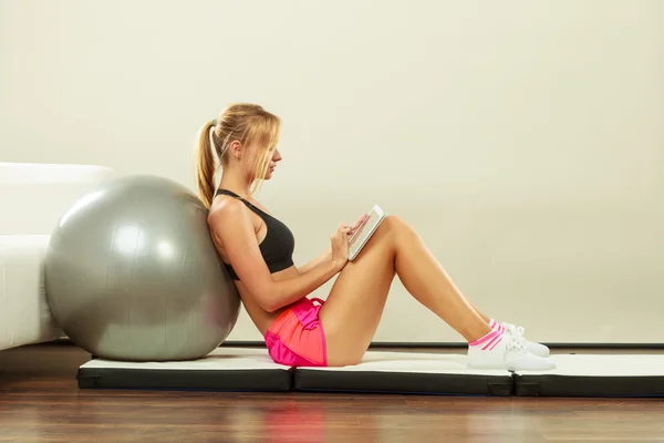 Fit woman sitting on floor with tablet pc