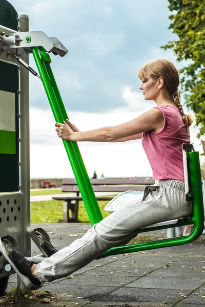 Active woman exercising on leg press outdoor.