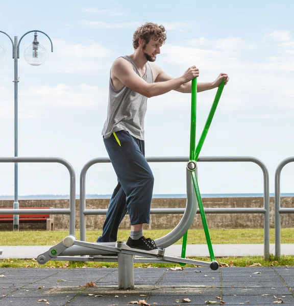 Active man exercising on elliptical trainer.