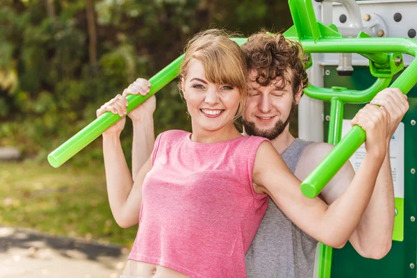 Man and woman exercising on pulldown outdoor.